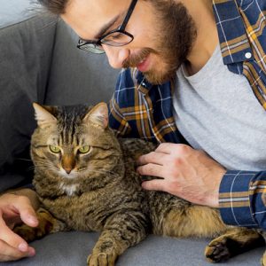 man with glasses petting cat