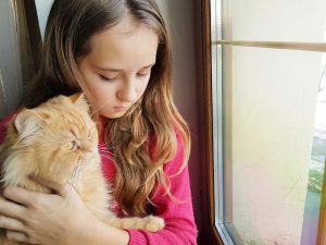 Young girl snuggling cat.